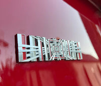 produktbillede fra forsiden viser Tesla Plaid Emblem/Badge Silver - TESLA