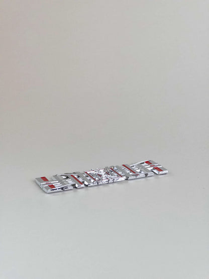 nærbillede af detaljer og materialer af Tesla Plaid Emblem/Badge Silver - TESLA