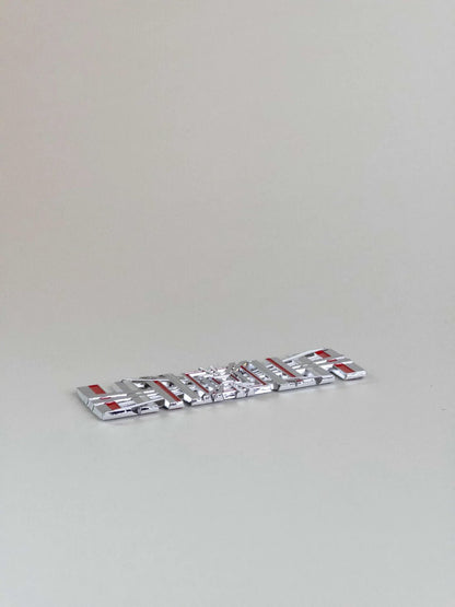 nærbillede af detaljer og materialer af Tesla Plaid Emblem/Badge Silver - TESLA