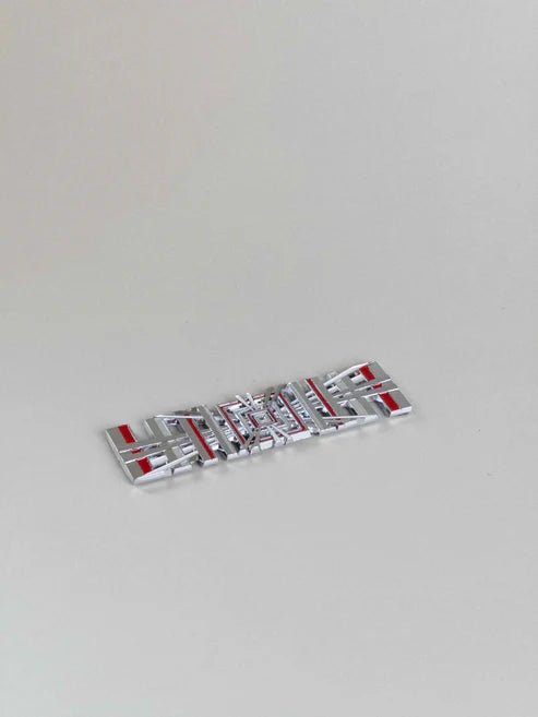 sidebillede, der viser profil og design af Tesla Plaid Emblem/Badge Silver - TESLA