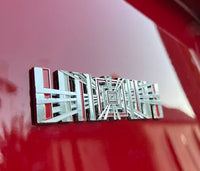 produktbillede fra forsiden viser Tesla Plaid Emblem/Badge Silver - TESLA